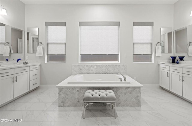 bathroom with marble finish floor, baseboards, and a garden tub