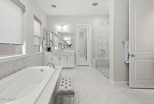 bathroom with marble finish floor, a garden tub, and visible vents
