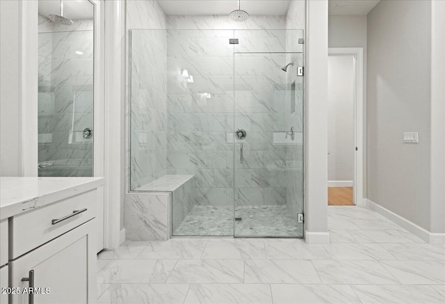 full bath with baseboards, marble finish floor, a marble finish shower, and vanity