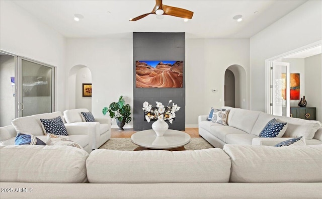 living area featuring baseboards, ceiling fan, wood finished floors, recessed lighting, and arched walkways