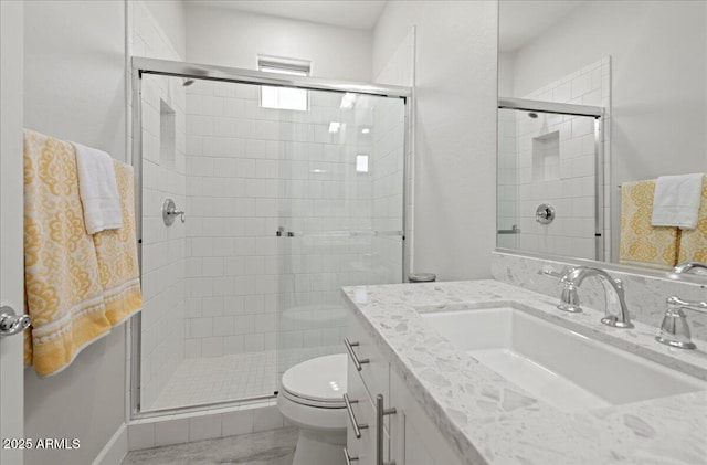 bathroom featuring toilet, a stall shower, and vanity