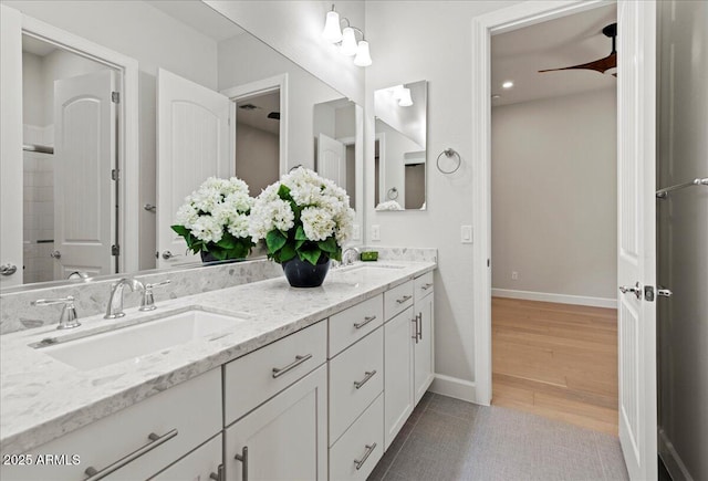 bathroom featuring double vanity, a sink, baseboards, and wood finished floors