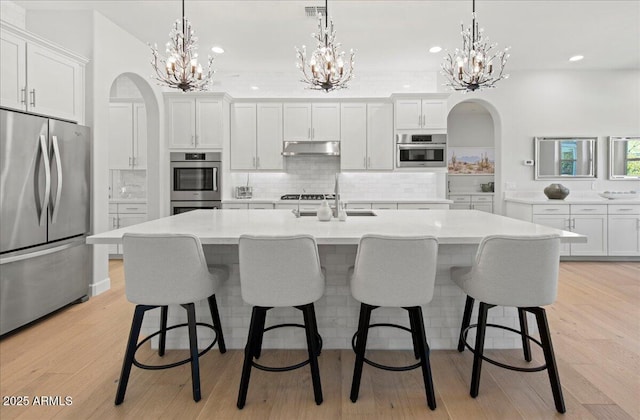 kitchen featuring an inviting chandelier, white cabinetry, appliances with stainless steel finishes, and under cabinet range hood