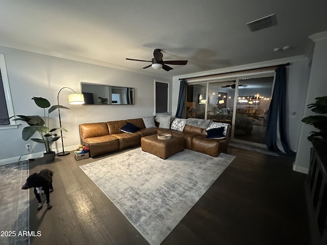 living area with baseboards, wood finished floors, visible vents, and crown molding