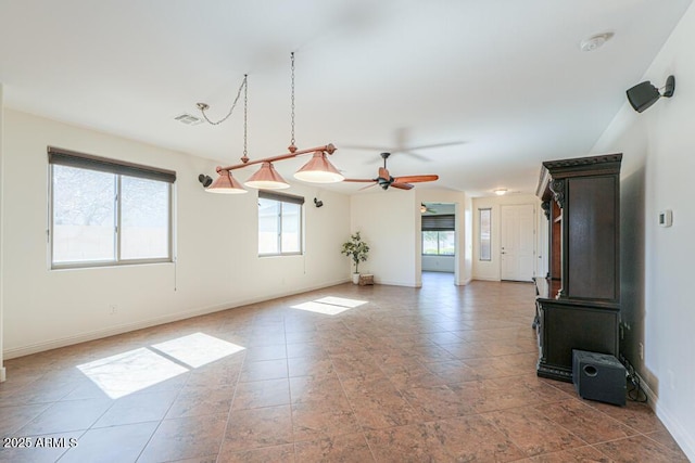 unfurnished living room with visible vents, baseboards, a wealth of natural light, and ceiling fan