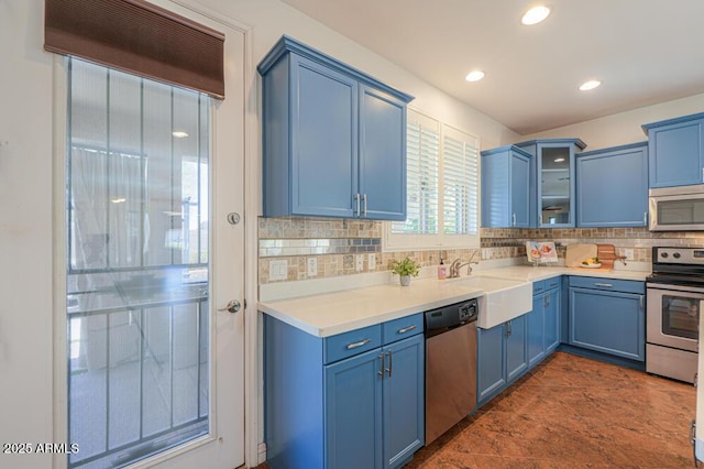 kitchen featuring blue cabinetry, a sink, stainless steel appliances, glass insert cabinets, and backsplash