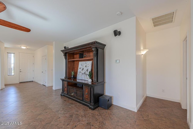 unfurnished living room with visible vents, ceiling fan, and baseboards