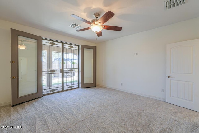 empty room featuring light carpet, visible vents, ceiling fan, and baseboards