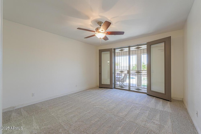 spare room featuring ceiling fan, baseboards, and light carpet