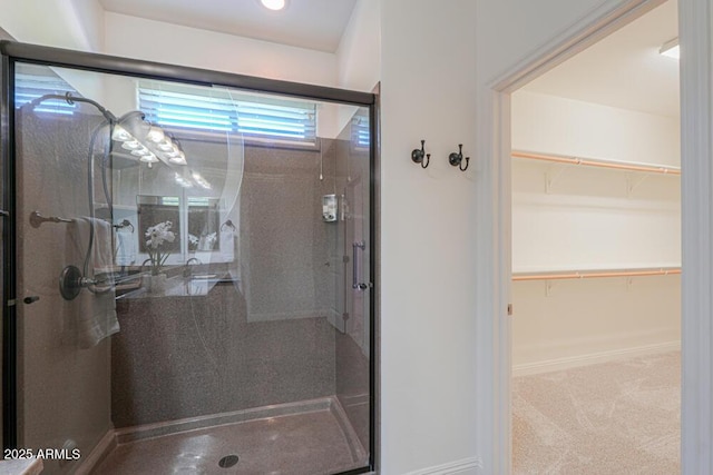 bathroom featuring a walk in closet, baseboards, and a shower stall