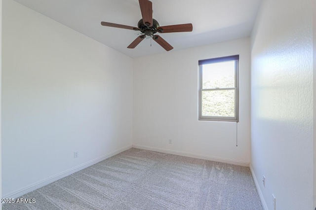 spare room with light carpet, a ceiling fan, and baseboards