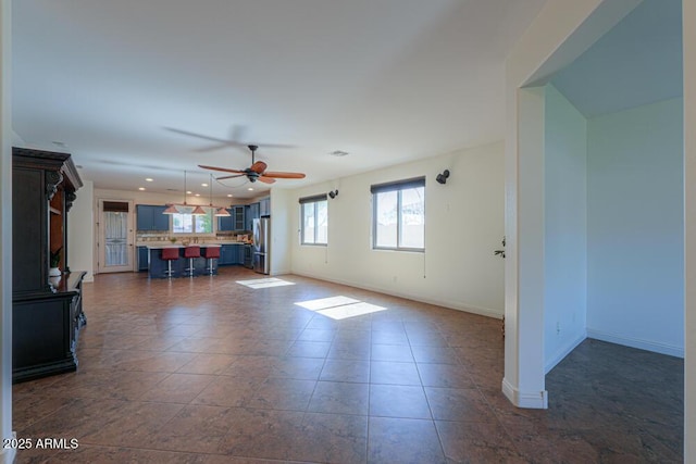 unfurnished living room featuring dark tile patterned floors, recessed lighting, a ceiling fan, and baseboards