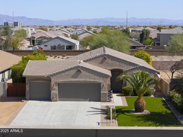 view of front of property featuring stucco siding, fence, a mountain view, concrete driveway, and an attached garage