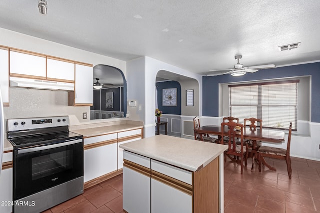 kitchen with a textured ceiling, white cabinets, and stainless steel electric range