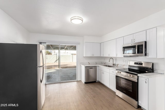 kitchen featuring sink, stainless steel appliances, white cabinetry, and light hardwood / wood-style floors