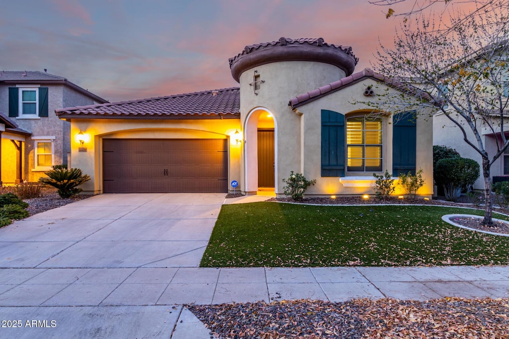 mediterranean / spanish-style house with a garage and a lawn