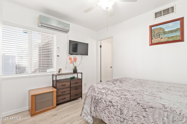 bedroom with a wall mounted air conditioner, ceiling fan, and light wood-type flooring