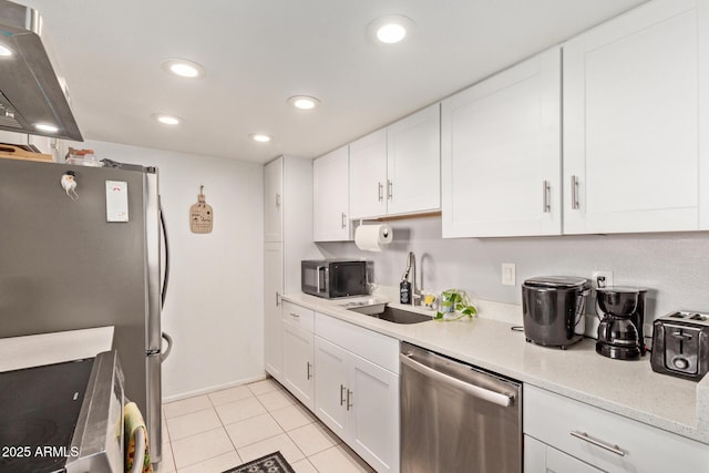 kitchen with light tile patterned flooring, appliances with stainless steel finishes, range hood, sink, and white cabinets