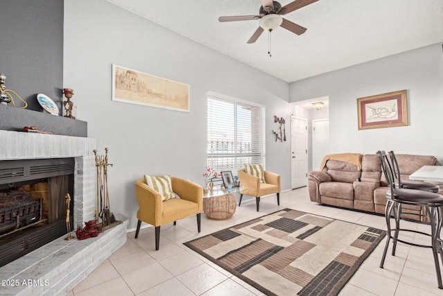 living room with a brick fireplace, light tile patterned floors, a textured ceiling, and ceiling fan