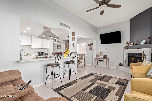 living room with light tile patterned floors, ceiling fan, and a brick fireplace