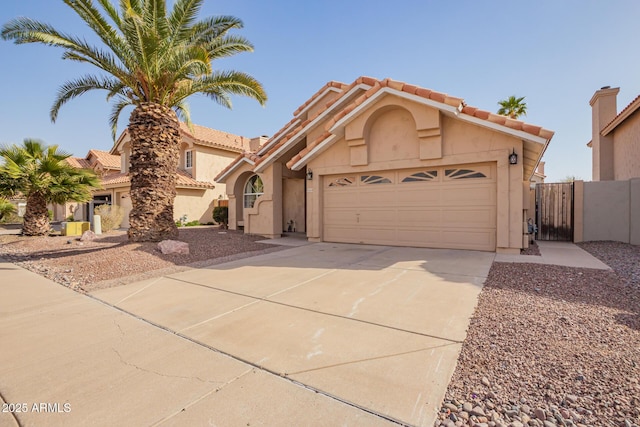 mediterranean / spanish home featuring an attached garage, a tile roof, driveway, a gate, and stucco siding