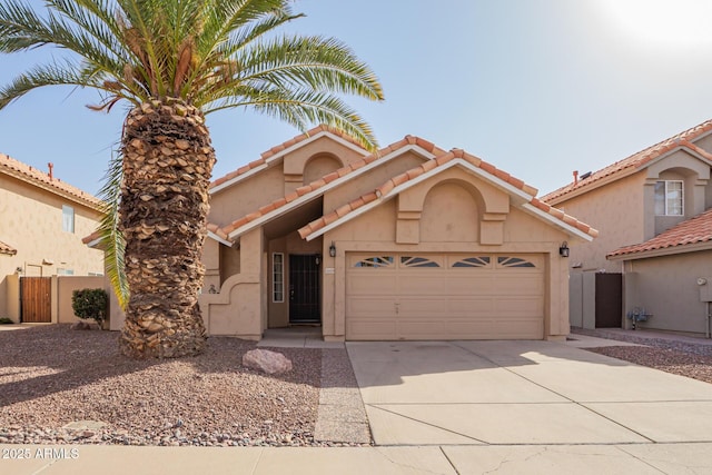 view of front facade featuring a garage, concrete driveway, a tiled roof, fence, and stucco siding