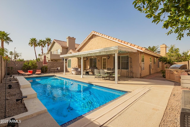 view of swimming pool with an outdoor kitchen, a patio area, a fenced backyard, and a fenced in pool