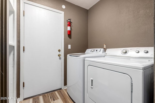 laundry area with laundry area, light wood finished floors, and washing machine and clothes dryer