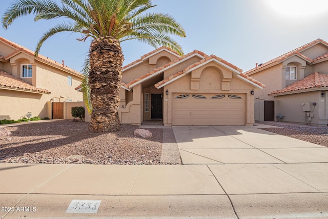 mediterranean / spanish home featuring a garage, fence, concrete driveway, a tiled roof, and stucco siding