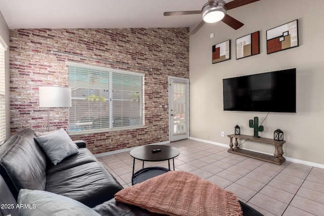 living area with a ceiling fan, baseboards, brick wall, and light tile patterned floors