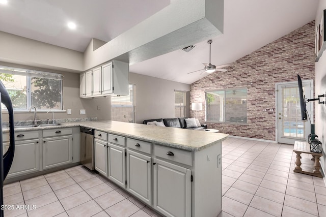 kitchen featuring open floor plan, a peninsula, a sink, light countertops, and stainless steel dishwasher