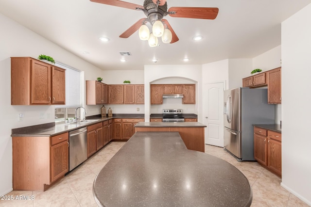 kitchen with sink, a center island, light tile patterned floors, appliances with stainless steel finishes, and ceiling fan