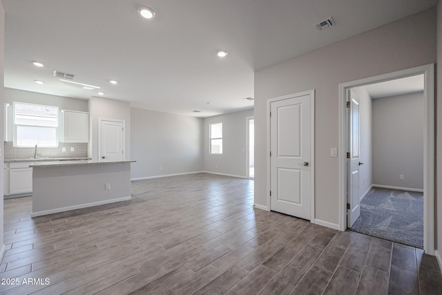 19320 N Diego Way, Maricopa, AZ 85138 - unfurnished living room featuring light wood-style floors, baseboards, recessed lighting, and a sink