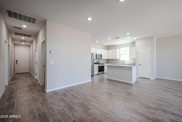 19320 N Diego Way, Maricopa, AZ 85138 - unfurnished living room with light wood finished floors, a sink, baseboards, and recessed lighting