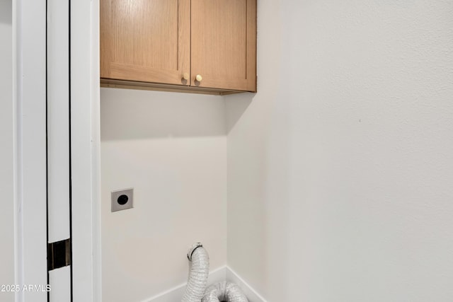 clothes washing area featuring hookup for an electric dryer and cabinet space