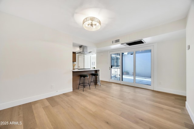 unfurnished living room with a notable chandelier, visible vents, baseboards, and light wood-style flooring