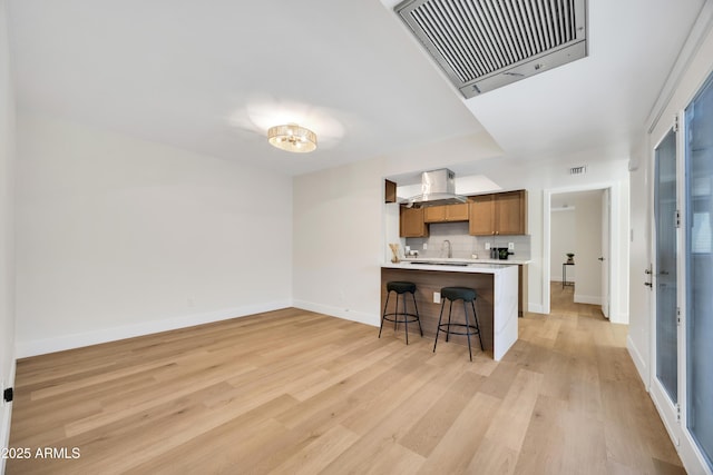 kitchen featuring tasteful backsplash, light countertops, visible vents, and light wood-type flooring