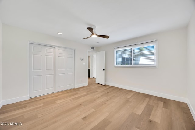 unfurnished bedroom with light wood-style flooring, a closet, and baseboards