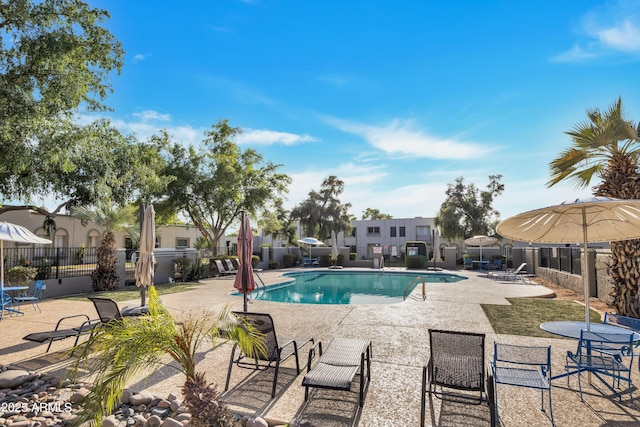 community pool with a patio area and fence