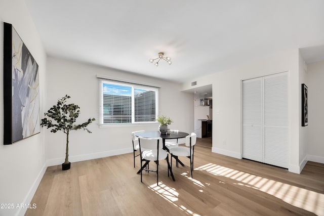 dining space with light wood-type flooring, baseboards, and visible vents