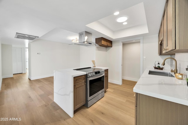 kitchen featuring visible vents, a raised ceiling, exhaust hood, a sink, and stainless steel electric range