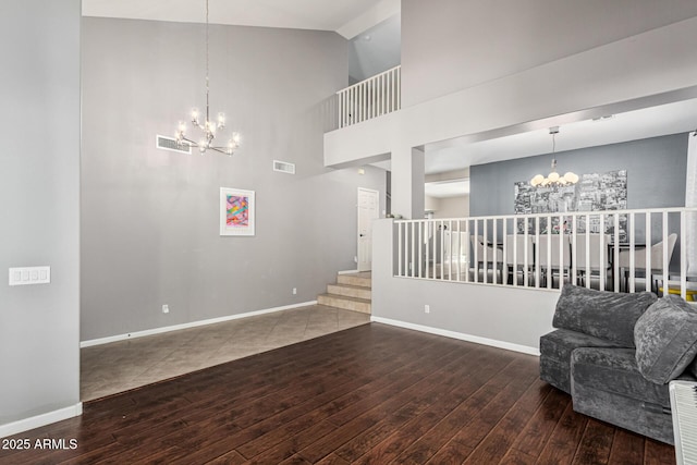 living room featuring a towering ceiling, wood-type flooring, and a chandelier