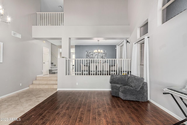 living area with a high ceiling, hardwood / wood-style floors, and an inviting chandelier