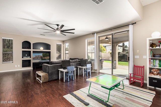 living room with dark hardwood / wood-style flooring, built in shelves, and ceiling fan