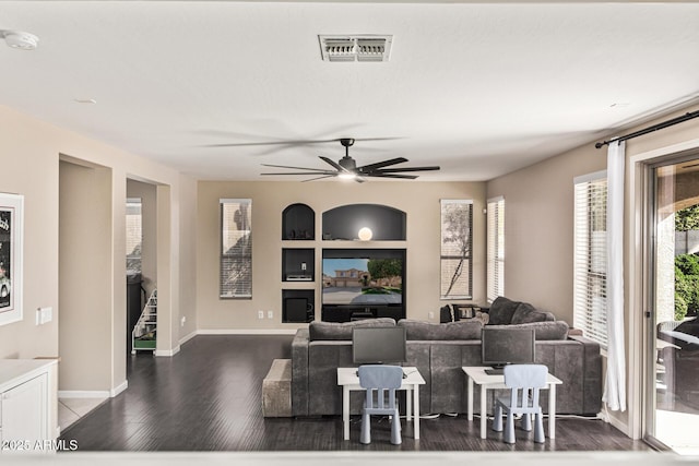 living room featuring ceiling fan, dark hardwood / wood-style floors, and built in features