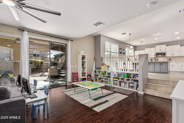 game room with dark wood-type flooring, ceiling fan, and a wealth of natural light