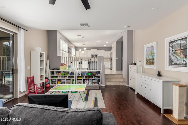 recreation room with a healthy amount of sunlight, dark hardwood / wood-style floors, and ceiling fan with notable chandelier