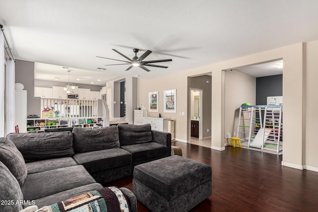 living room with dark hardwood / wood-style flooring and ceiling fan with notable chandelier