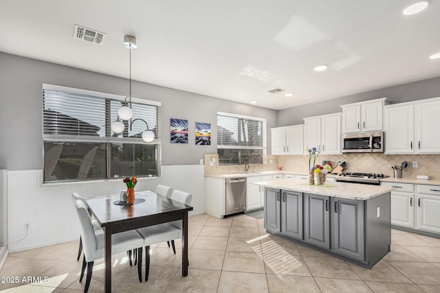 kitchen featuring hanging light fixtures, a center island, white cabinets, and appliances with stainless steel finishes