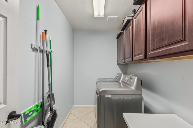 laundry area featuring independent washer and dryer, cabinets, a textured ceiling, and light tile patterned flooring